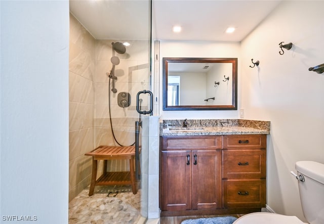 bathroom featuring toilet, a shower stall, and vanity