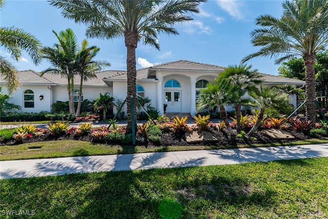 mediterranean / spanish house with a tiled roof, a front lawn, and stucco siding