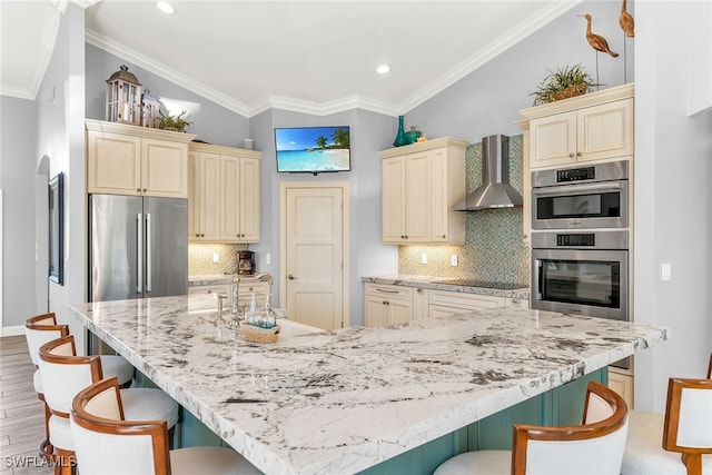 1015 Goldenrod Ave, Marco Island, FL 34145 - kitchen featuring wall chimney exhaust hood, appliances with stainless steel finishes, cream cabinets, and a kitchen breakfast bar