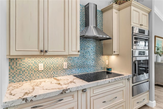 1015 Goldenrod Ave, Marco Island, FL 34145 - kitchen with wall chimney exhaust hood, black electric stovetop, stainless steel double oven, cream cabinetry, and a warming drawer