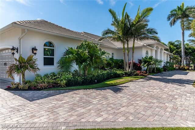 1015 Goldenrod Ave, Marco Island, FL 34145 - view of side of home featuring a garage, a tile roof, and stucco siding