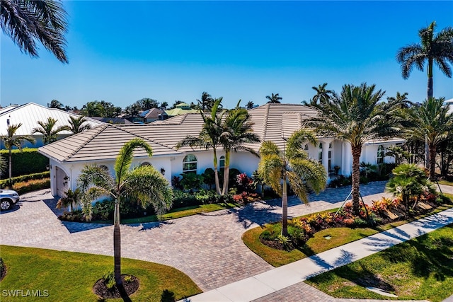 view of front of property with a tile roof, a front lawn, decorative driveway, and stucco siding