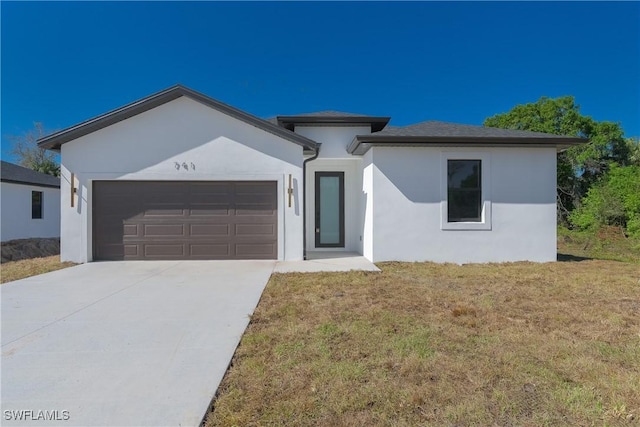 view of front of house with an attached garage, driveway, a front lawn, and stucco siding