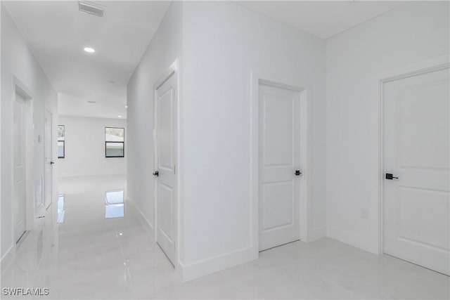 hall featuring baseboards, visible vents, and recessed lighting