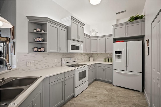 kitchen with white appliances, visible vents, gray cabinetry, open shelves, and a sink