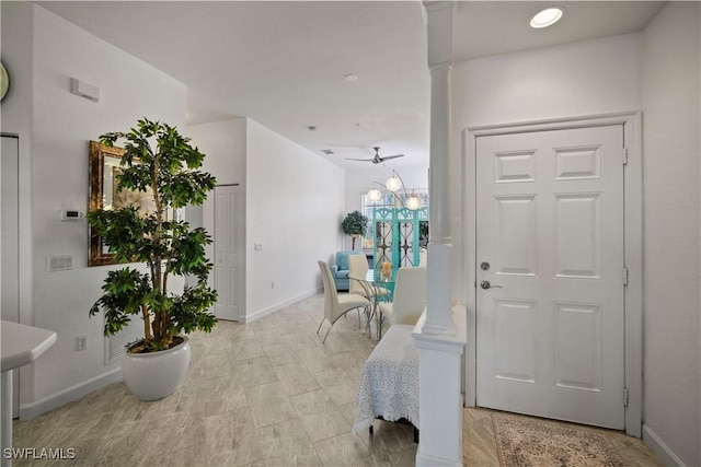 entryway featuring baseboards, a ceiling fan, and ornate columns