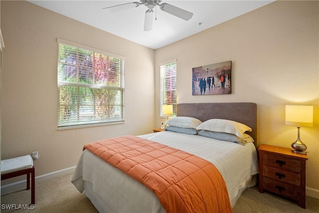 carpeted bedroom featuring multiple windows, a ceiling fan, and baseboards