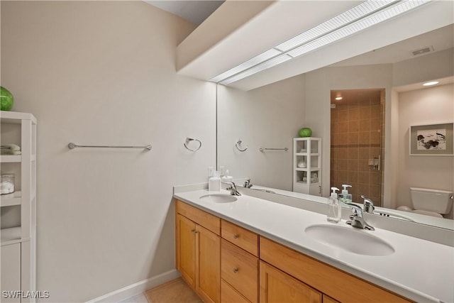 full bathroom with toilet, double vanity, visible vents, and a sink