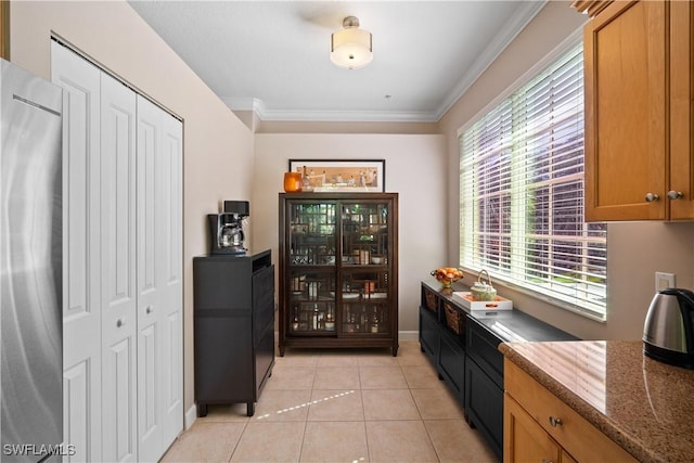 bar featuring ornamental molding, light tile patterned flooring, baseboards, and stainless steel refrigerator