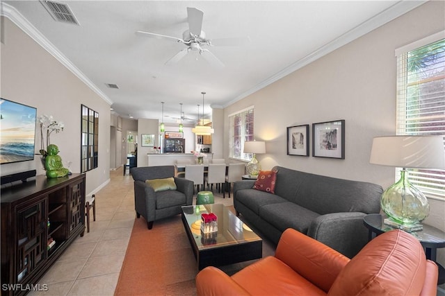 living room with a ceiling fan, visible vents, crown molding, and light tile patterned flooring