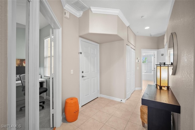foyer with visible vents, light tile patterned flooring, ornamental molding, and a healthy amount of sunlight