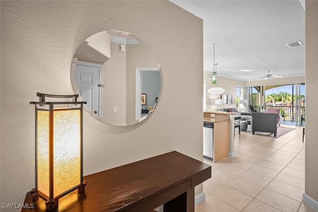 hallway with ornamental molding, a textured wall, visible vents, and light tile patterned floors