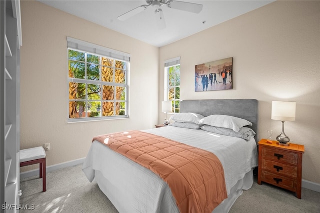 carpeted bedroom with ceiling fan, baseboards, and multiple windows