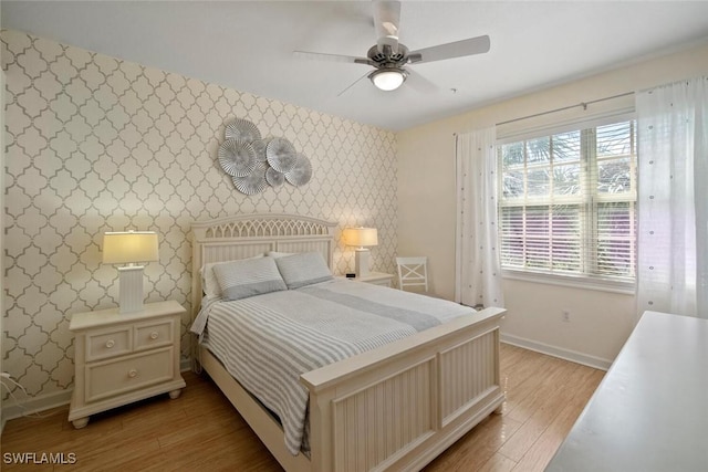 bedroom featuring wallpapered walls, baseboards, and light wood-style floors