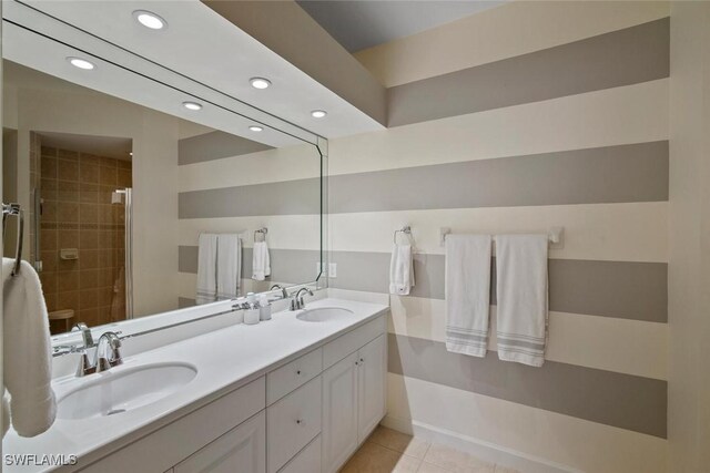 full bathroom featuring double vanity, a sink, a tile shower, and tile patterned floors