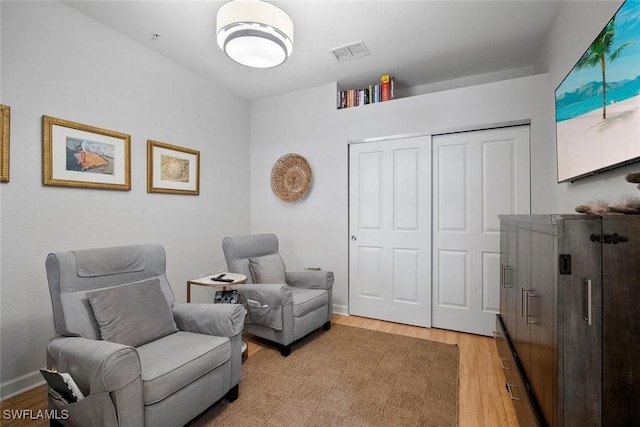 sitting room featuring visible vents, light wood-style flooring, and baseboards