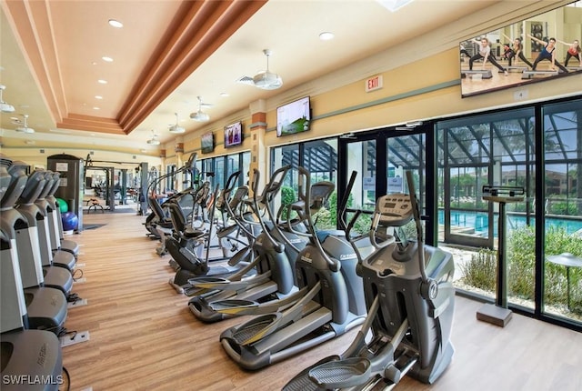 exercise room with a tray ceiling and wood finished floors