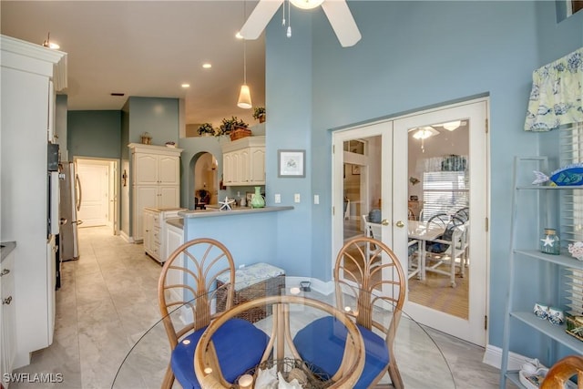 dining room featuring arched walkways, light tile patterned flooring, a high ceiling, a ceiling fan, and french doors