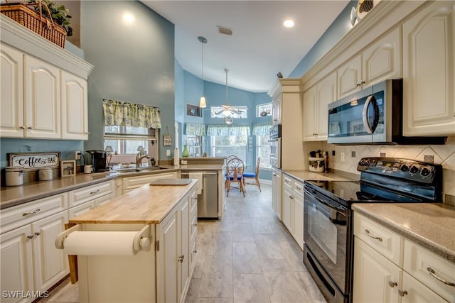 kitchen featuring butcher block counters, decorative backsplash, appliances with stainless steel finishes, a sink, and a peninsula