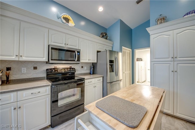 kitchen featuring lofted ceiling, light countertops, decorative backsplash, appliances with stainless steel finishes, and white cabinetry