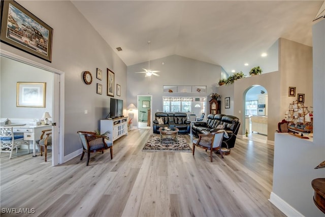 living area featuring baseboards, visible vents, arched walkways, light wood-type flooring, and high vaulted ceiling