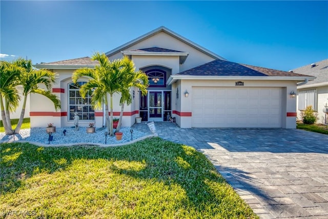 single story home with a garage, stucco siding, decorative driveway, and french doors