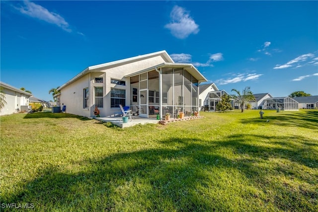 rear view of property featuring central AC unit, a sunroom, a lawn, stucco siding, and a patio area