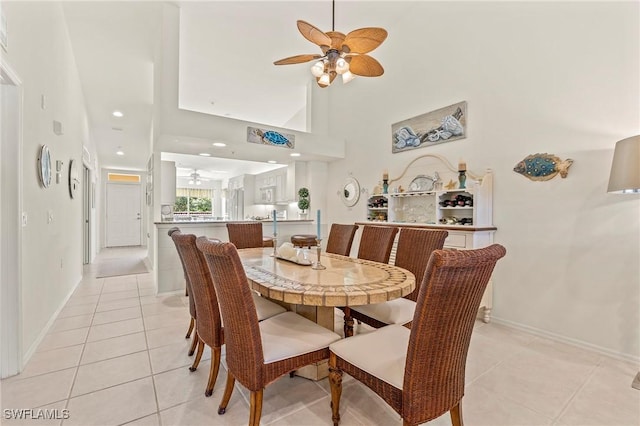 dining room featuring light tile patterned floors, a high ceiling, a ceiling fan, and baseboards