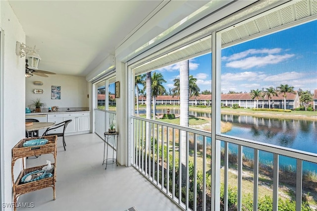 sunroom / solarium with a ceiling fan and a water view