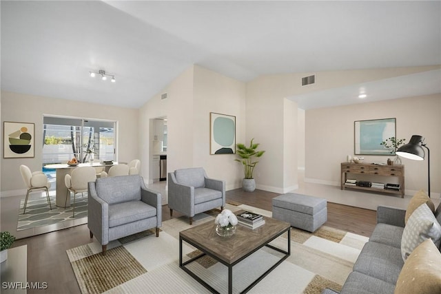 living area featuring baseboards, visible vents, vaulted ceiling, and wood finished floors