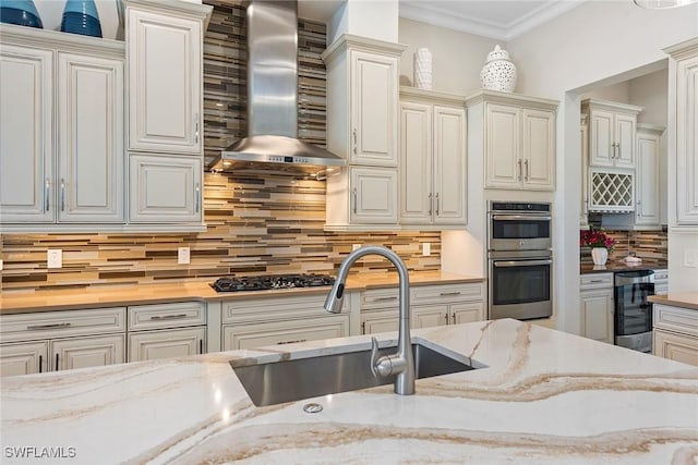 kitchen with gas stovetop, stainless steel double oven, a sink, beverage cooler, and wall chimney exhaust hood