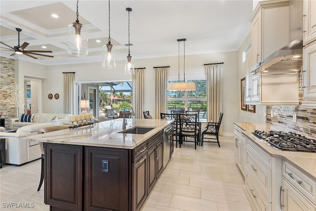 kitchen with dark brown cabinetry, stainless steel appliances, a sink, open floor plan, and backsplash