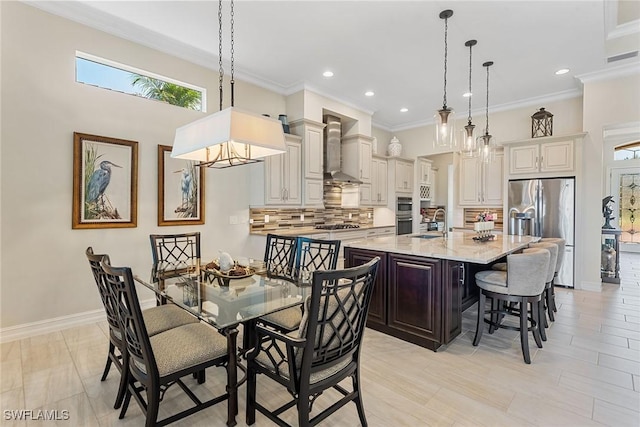 kitchen featuring a sink, wall chimney range hood, stainless steel refrigerator with ice dispenser, tasteful backsplash, and a large island with sink