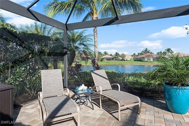 view of patio featuring glass enclosure and a water view