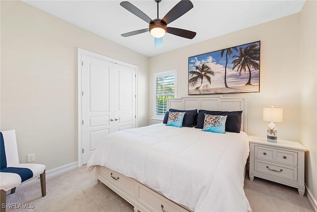 bedroom with a closet, light colored carpet, ceiling fan, and baseboards