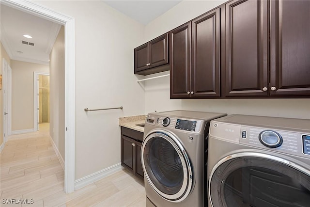 laundry room with visible vents, washing machine and clothes dryer, cabinet space, and baseboards