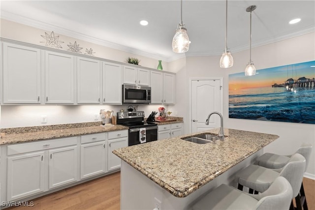 kitchen featuring crown molding, appliances with stainless steel finishes, white cabinets, a sink, and a kitchen bar