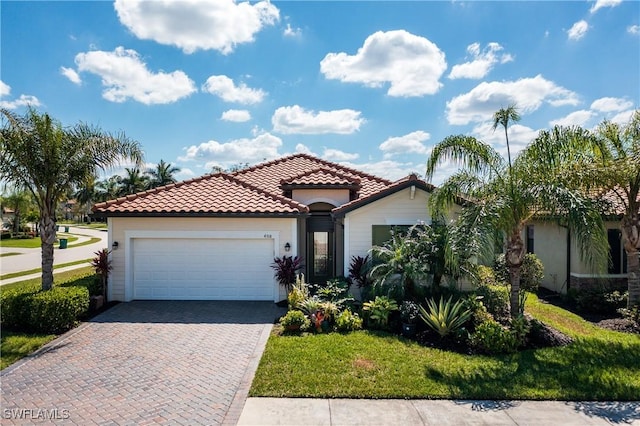 mediterranean / spanish home featuring a garage, a tile roof, a front lawn, and decorative driveway