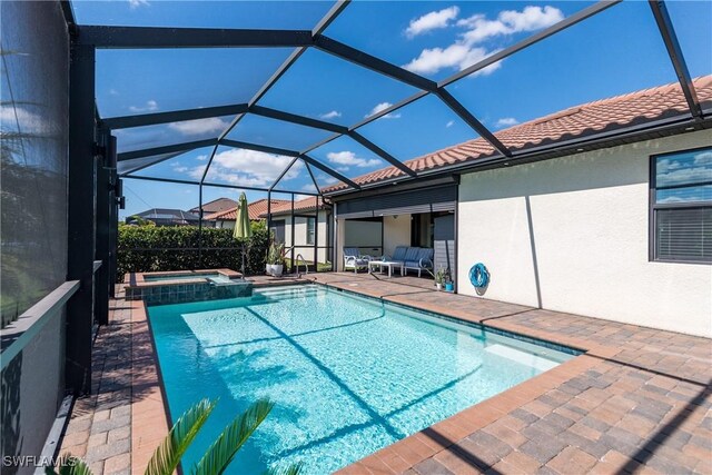 view of swimming pool with glass enclosure, a pool with connected hot tub, a patio area, and outdoor lounge area