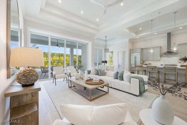 living area featuring a tray ceiling, a towering ceiling, and light wood-style floors