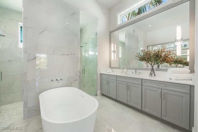 bathroom featuring marble finish floor, a marble finish shower, a soaking tub, and vanity