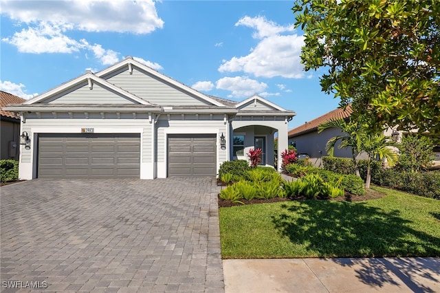 view of front of home with a garage, a front yard, and decorative driveway