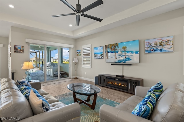 living room with recessed lighting, a glass covered fireplace, ceiling fan, wood finished floors, and baseboards