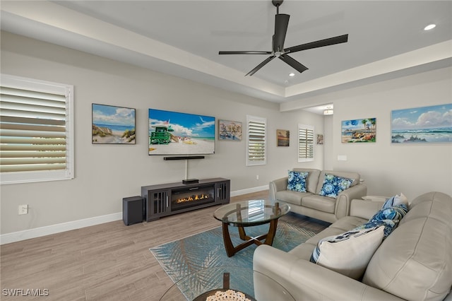 living room featuring recessed lighting, light wood-style flooring, baseboards, and a glass covered fireplace