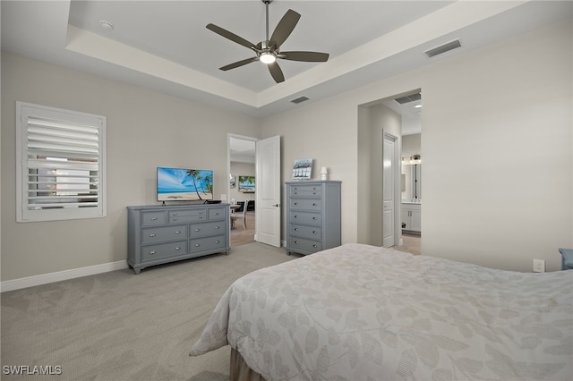 bedroom featuring a tray ceiling, visible vents, light carpet, ceiling fan, and baseboards