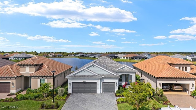 view of front of property with a garage, a tile roof, a residential view, and decorative driveway