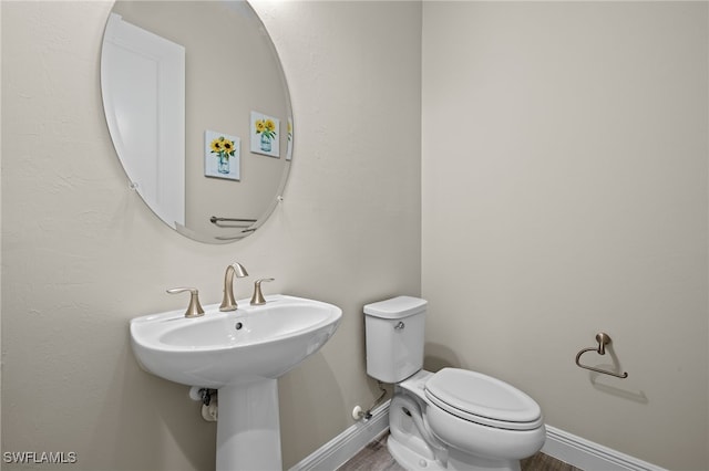 bathroom featuring a sink, wood finished floors, toilet, and baseboards