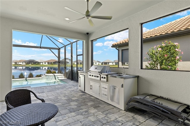 view of patio with a lanai, area for grilling, a sink, a ceiling fan, and exterior kitchen