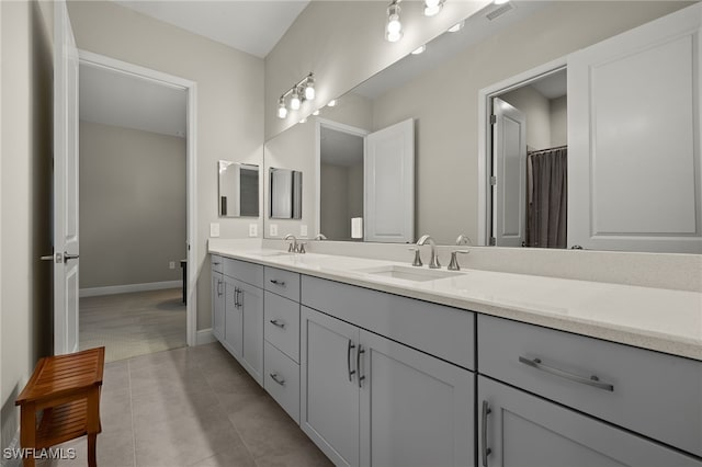 bathroom with tile patterned flooring, a sink, visible vents, baseboards, and double vanity