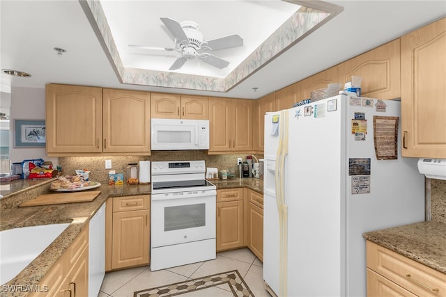 kitchen with a tray ceiling, white appliances, light brown cabinets, and light tile patterned floors